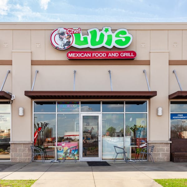 The exterior of Luis Mexican Food and Grill, featuring its vibrant green and red sign, and outdoor seating.