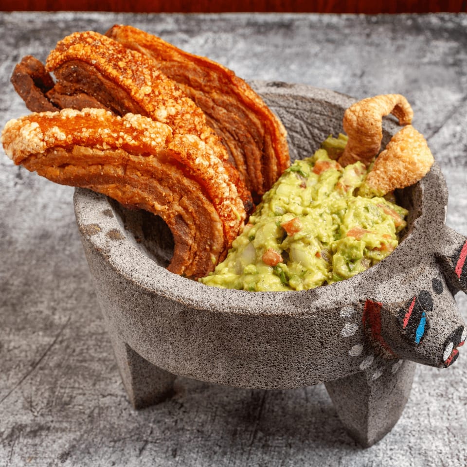 Crispy chicharrones and fresh guacamole served in a traditional molcajete at Luis Mexican Food & Grill.