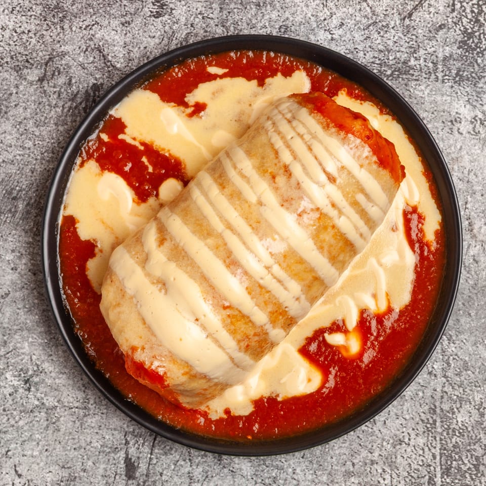 Luis Mexican Food & Grill's burrito covered in red sauce and white cheese sauce, top-down view.