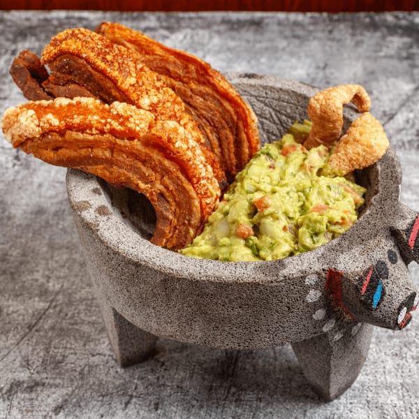 Crispy chicharrones and fresh guacamole in a decorative molcajete at Luis Mexican Food & Grill.